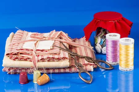 Glass Jar, Scissors, Thimbles and Spools Isolated on Blue 