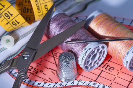 Sewing Thread Spools, Metal Scissors, Metal Thimble, Sewing Ruler and Needle on Fabric 