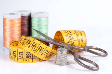 Old Metal Scissors, Tailor Tape Measure, Metal Thimble and Sewing Thread Spool Isolated on White