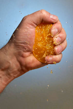 Male Hand Squeezing an Orangeの写真素材