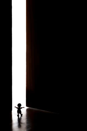 Little Doll Overlooking the Unknown Through a Doorの写真素材