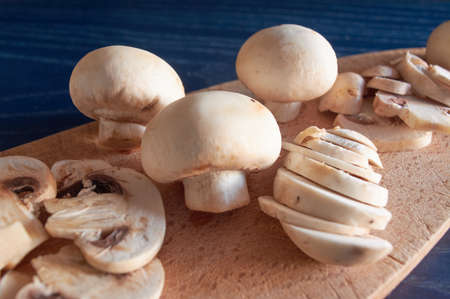 whole and sliced ââmushrooms, on wooden board, on blue backgroundの写真素材