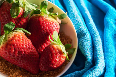 three strawberries and sugar cane on blue cloth background in white bowlの写真素材