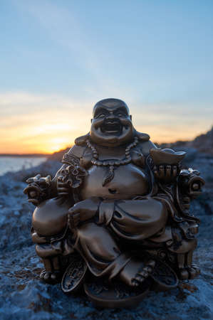 Buddha figure, at sunset, on a cliff in the seaの写真素材