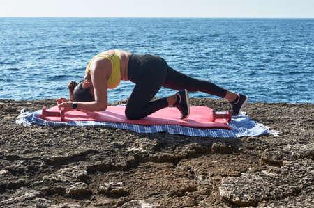 FITNESS WOMAN IN SPORTS SET TRAINING WITH ELASTIC BAND, WEIGHTS, GYM EXERCISES, IN FRONT OF THE...