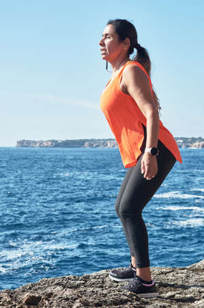 Latin woman, middle-aged, wearing sportswear, training, doing physical exercises, plank, sit-ups,...