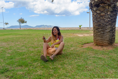 portrait of a latin woman smiling, having fun, on vacation in mallorca posing on a warm spring summer day, under a palm tree, hollidays conceptの写真素材
