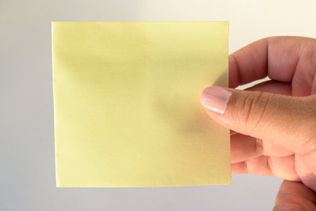 Woman's hand with painted nails holding blank letter paper on pure white background.の写真素材