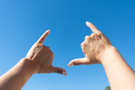 womans hands showing surfer sign against blue sky backgroundの写真素材