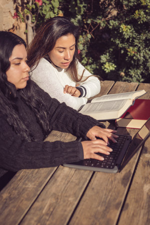 young mother helps daughter do college work, in home gardenの写真素材