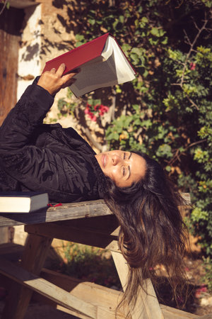 beautiful woman reading in the garden, looking at the cameraの写真素材