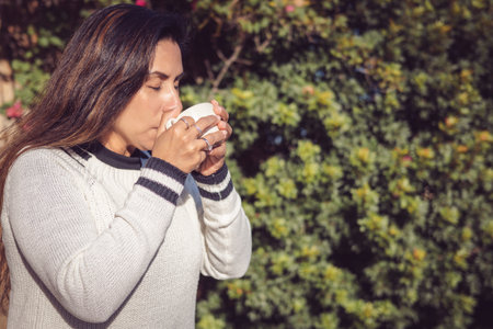 Break to Enjoy, Latina Woman Enjoying the Garden with Coffeeの写真素材