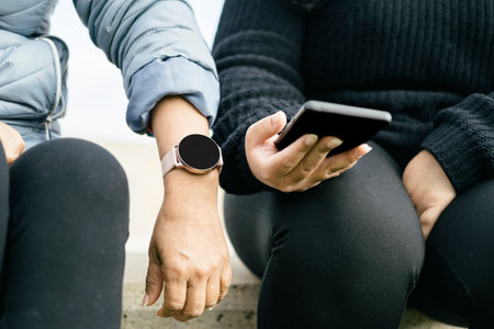two beautiful Latina women are proudly displaying their new smartwatch and smartphone. Hispanic ladies are keeping up with the latest technology trendsの写真素材