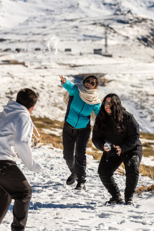 latin family at ski resort, in granada sierra nevada having fun throwing snowballs, playing on a sunny day,andalucia, spain,の写真素材