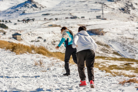 Latin boys running through the snow on a sunny day in the mountainsの写真素材
