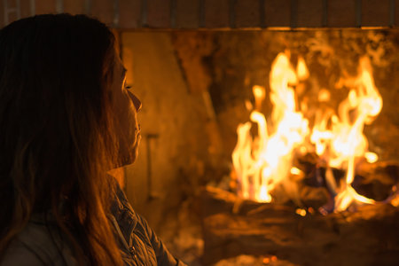 Latin woman in front of the fireplace, in a moment of relaxation and peace during the harsh winter days in Europe.の写真素材