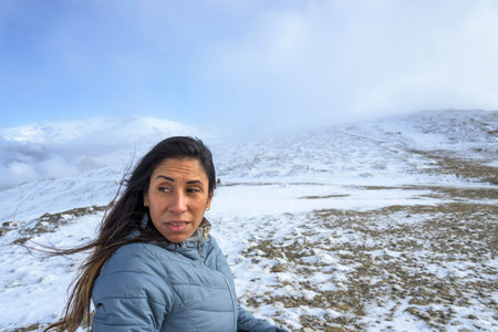 middle-aged latina woman on a snow-capped mountain in a blizzard,の写真素材
