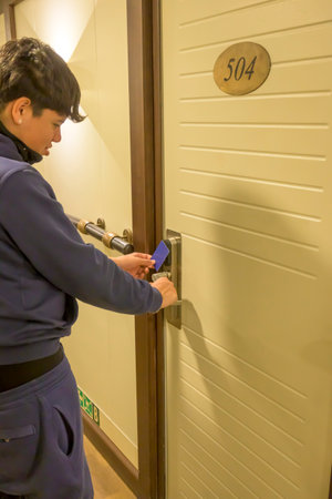 Latin young men opens a door with a keycard in a hallway, key electronic lock, hotel room, holidays in mallorca, spainの写真素材