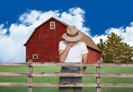 sad farmer with a red barn in the backの写真素材
