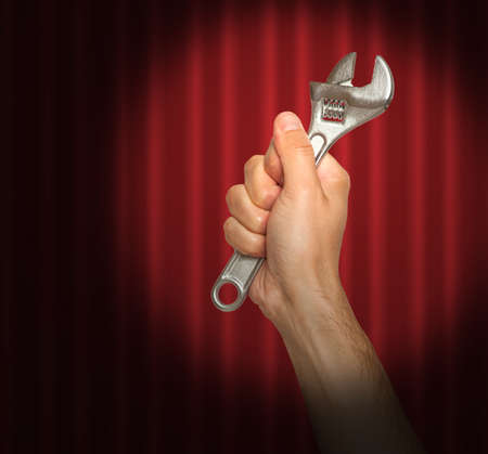 Hand holding a wrench under a spot lightの写真素材