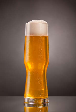 Glass of fresh beer with cap of foamの写真素材