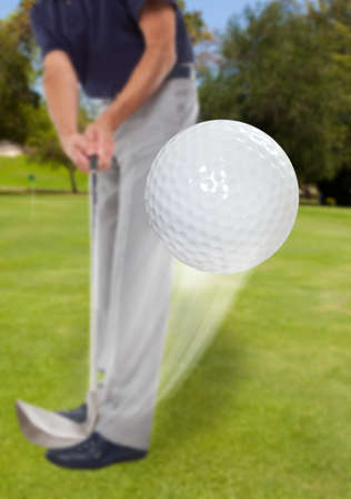 A golf ball just coming off the tee from a golfer in swingの写真素材