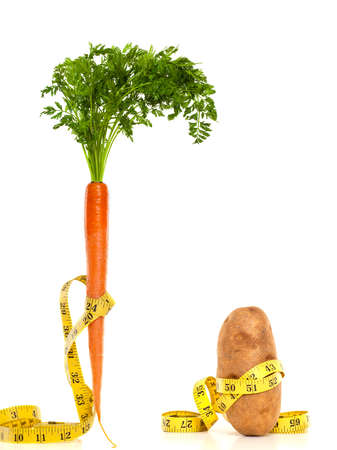 A carrot and potato with measuring tape around them. Diet conceptの写真素材