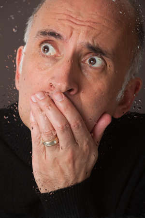 Scared man behind a glass window