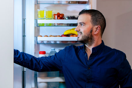 Young man on a diet - Opening the fridge - Healthy foodの写真素材