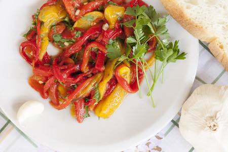 Dish of red and yellow peppers with parsley and garlicの写真素材
