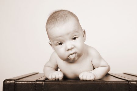 Young baby lying on his tummy on an old style suitcaseの写真素材