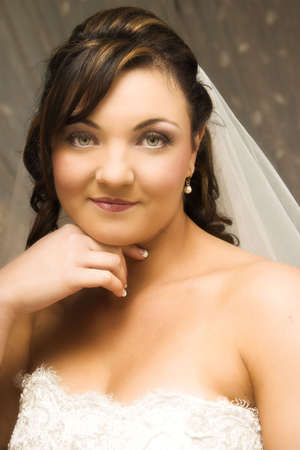 Beautiful brunette bride wearing pearl earrings and a veilの写真素材