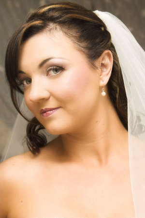 Beautiful brunette bride wearing pearl earrings and a veilの写真素材