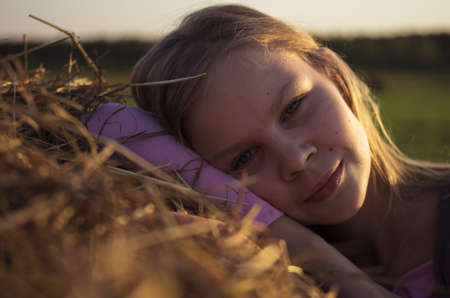 Portrait of teenage girl in the field with corn ears and straw