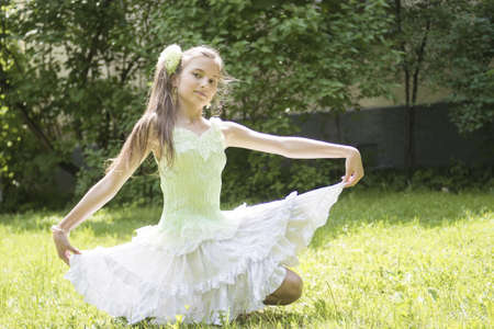 teenage girl sitting in light dress on the grassの写真素材