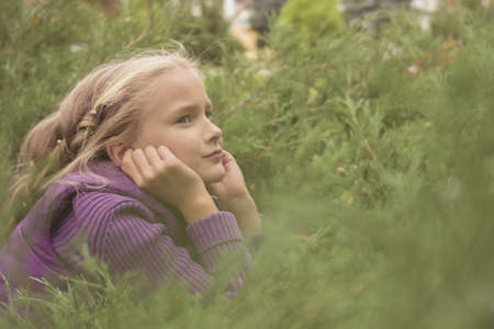 Little preteen girl playing outdoor in bush in park at autumnの写真素材