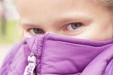 Little preteen girl looking throw vest outdoor in park at autumnの写真素材