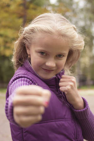 Little preteen girl shows a fist outdoor in park at autumnの写真素材
