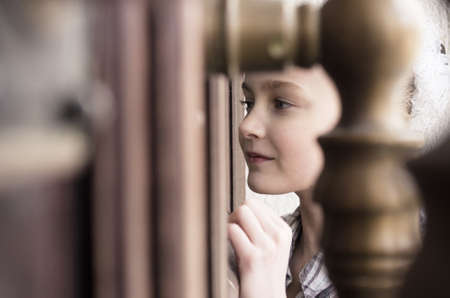 little girl looking throw door window searching for somethingの写真素材