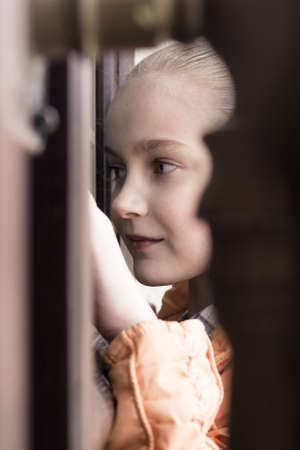 little girl looking throw door window searching for somethingの写真素材