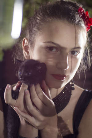 young beatifull girl in black dress playing witch in the courtyard with kittenの写真素材