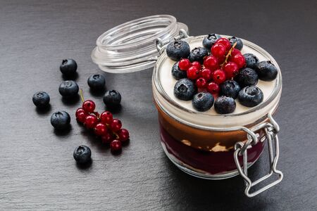 Layered cake dessert in jar, chocolate and fruit cream, decorated with berries.の写真素材