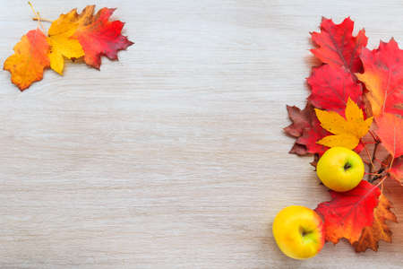 Autumn decor from leaves and yellow apple on a wooden background. Flat lay autumn composition with copy space.の写真素材