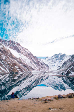 Redhead young adult woman posing in front of Andes Mountains with a blue jacket and looking away from the camera.の写真素材