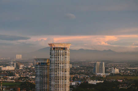 A building in focus with a mountain background covered in smog in the metropolitan area of Karawaci, Tangerang.のeditorial素材