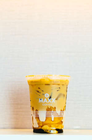An illustrative editorial of the Maxx Coffee Iced Coffee with caramel in the center with a light pink background.のeditorial素材