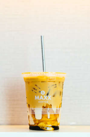An illustrative editorial of the Maxx Coffee Iced Coffee with caramel and a stainless steel straw in the center with a light pink background.のeditorial素材