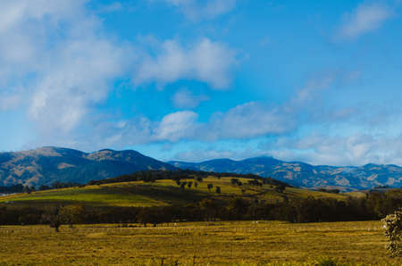 Dramatic view of Minas Gerais hills and farms in different tones of green and a cloudy sky in the...