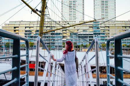A redhead brazilian woman in her 20s entering a big boat parked in the business area of Puerto...