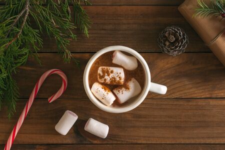 Christmas hot chocolate with marshmallows and xmas ornaments on wooden table